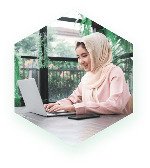 A girl sitting at a table with a laptop and working on a freelance project - Dream Peak IT